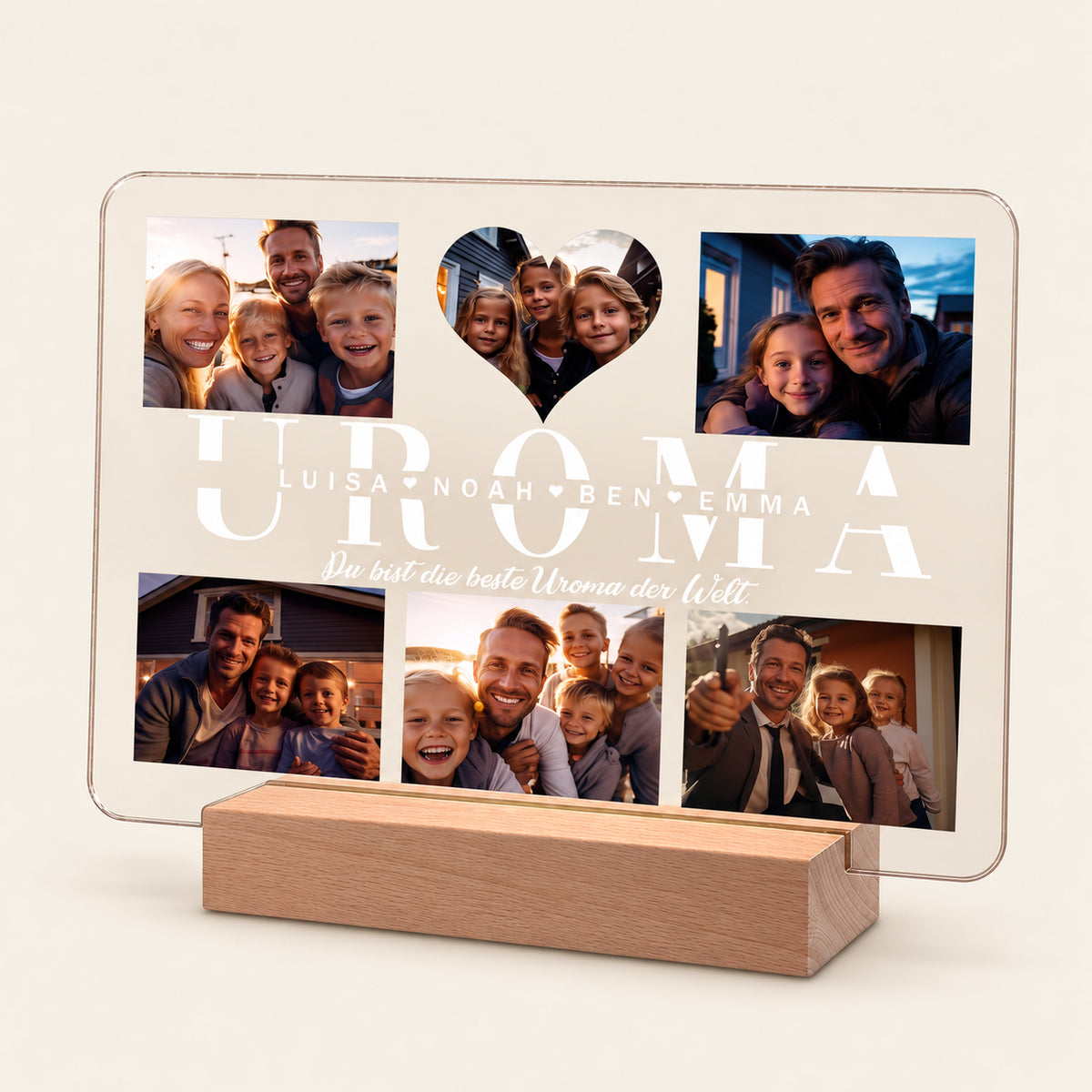 Beleuchtete Acryl-Fotocollage auf einem Holz-LED-Sockel, die fünf Familienfotos und einen herzförmigen Ausschnitt zeigt. Der Text lautet 'UROMA', die Namen 'Luisa, Noah, Ben, Emma' und 'Du bist die beste Uroma der Welt.'