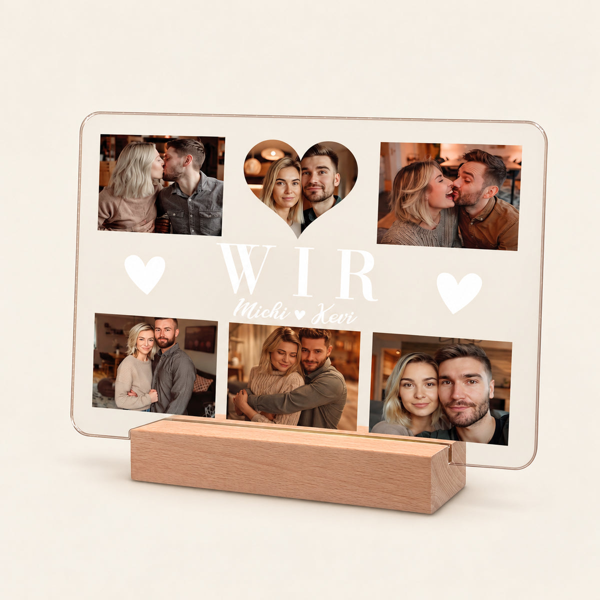 Personalisierte Acryl‑Foto‑Collage‑Anzeige auf einem hölzernen LED‑Ständer, mit 6 Paar‑Fotos rund um ein herzförmiges Mittelbild. Weißer Text lautet „WIR“ und „Michi & Kevi“ mit Herz‑Icons. Warmes Rücklicht leuchtet durch das Panel.