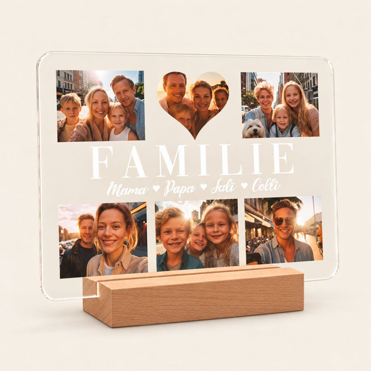 Personalisierte Acryl‑Foto‑Nachtlampe auf einem Holz‑LED‑Ständer, die sechs Familienfotos, ein herzförmiges Mittel‑Foto und weißen Text „FAMILIE“ mit den Namen „Mama, Papa, Sali, Colli“ zeigt. In einer warmen Wohnumgebung gezeigt.