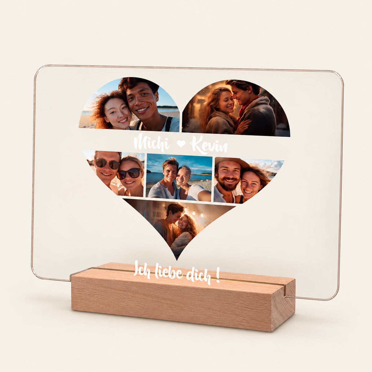 Beleuchtetes Acryl-Fotodisplay auf einem hölzernen LED-Sockel mit einer herzförmigen Collage aus fünf Paarfotos. Weißer Text lautet 'Michi heart Kevin' und 'Ich liebe dich!' und leuchtet gegen einen warmen beigefarbenen Hintergrund.