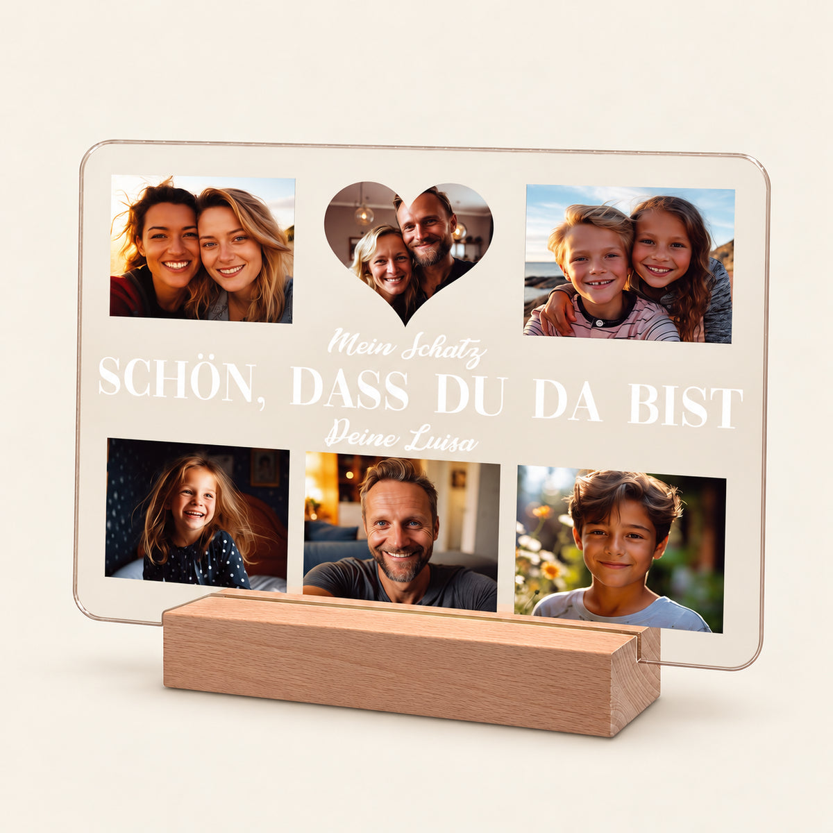 Personalisierter Acryl-Fotodisplay auf einem Holzständer mit fünf Familienfotos, angeordnet um einen weißen deutschen Text: „Mein Schatz / SCHON, DASS DU DA BIST / Deine Luisa“. Das mittlere Foto ist herzförmig. Warmes, rückseitiges Leuchten sichtbar.