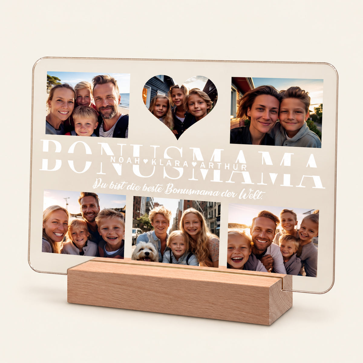 Beleuchtete Acryl‑Fotocollage‑Plakette auf einem Holz‑LED‑Grund, mit fünf Familienfotos und einem herzförmigen Ausschnitt. Großer weißer Schriftzug 'BONUSMAMA' mit den Namen 'Noah, Klara, Arthur' und darunter deutschsprachiger Text.